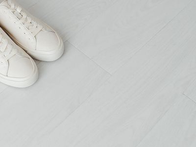 A pair of clean running shoes on a wooden floor.