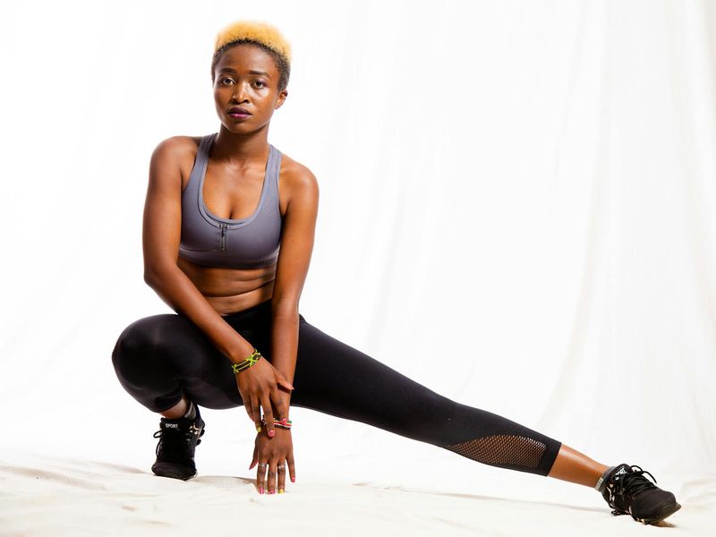 Athletic person doing a dynamic stretch in a bright studio.